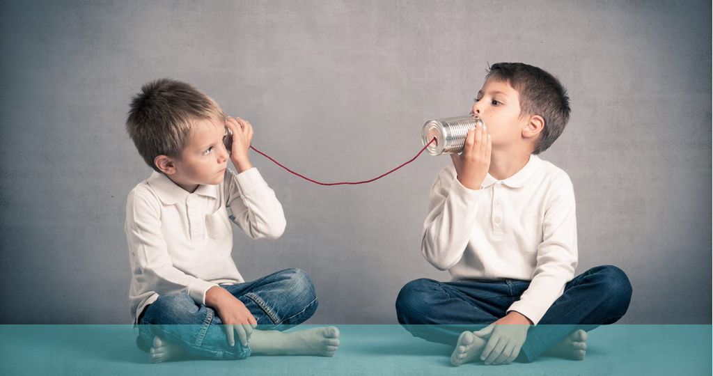 錫と糸の電話を使って話す二人の子供の写真
