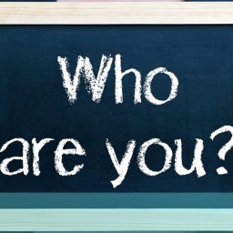 person holding chalk board that says who are you